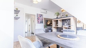 Moderni ruokailutila, jossa on suuri pöytä, pehmustetut tuolit ja koristeellinen pöytäkoriste.