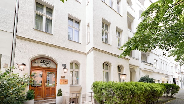 A hotel entrance with a wooden double door, a signboard, and a paved pathway leading to the entrance. - Arco Smart City Hotel - Berlin KU'DAMM (Berlin)