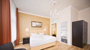 A hotel room with a bed, a nightstand, a dresser, a chair, and a chandelier. - Arco Smart City Hotel - Berlin KU'DAMM (Berlin)