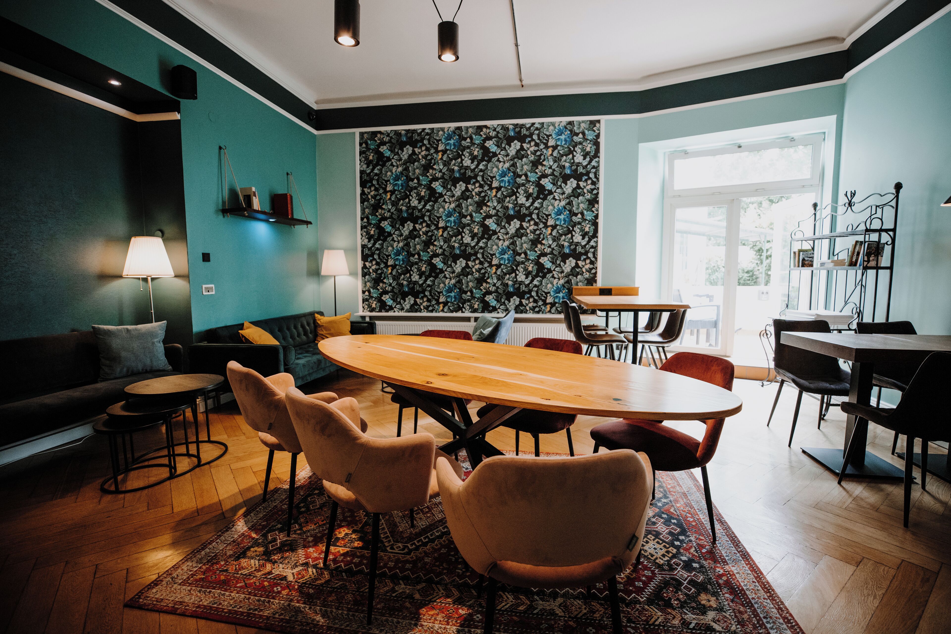Un espace repas moderne avec une table en bois, des chaises rembourrées et un tapis à motifs.