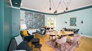A modern living room with a sofa, chairs, a dining table, and a patterned rug. - Arco Smart City Hotel - Berlin KU'DAMM (Berlin)