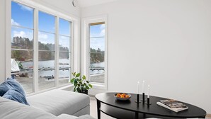 Ein modernes Wohnzimmer mit großem Fenster mit Blick auf ein Gewässer und einen Steg.