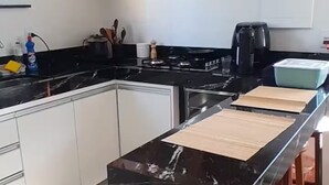 Una cocina moderna con una isla de mármol negro, armarios de madera y una cafetera.