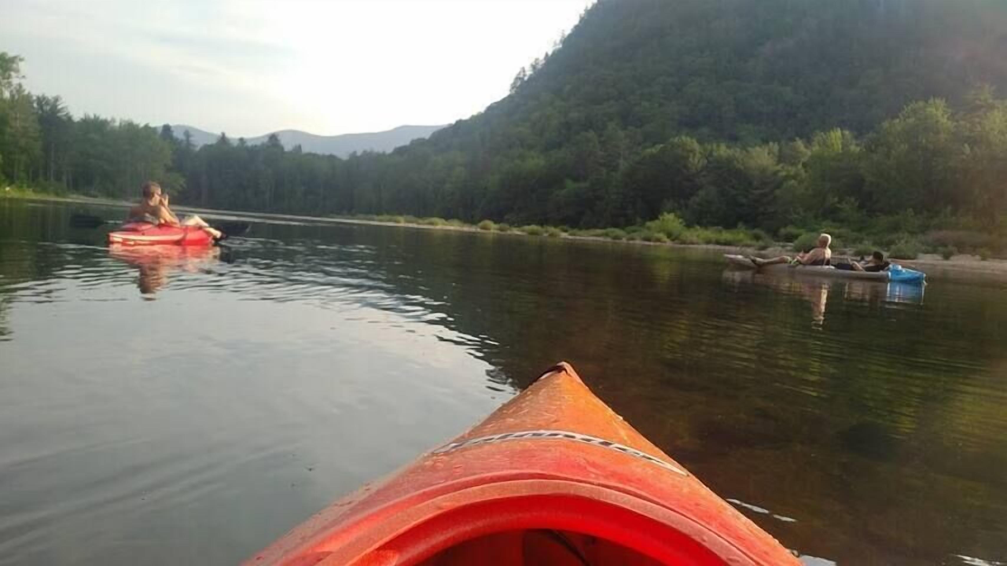 Ein ruhiger Fluss mit Kajaks und einem Kanu.