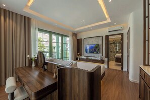 A modern hotel room with a wooden desk, a comfortable sofa, a television, and a bathroom visible through an open door. - Green Villas Tropical Phu Quoc (Phu Quoc)