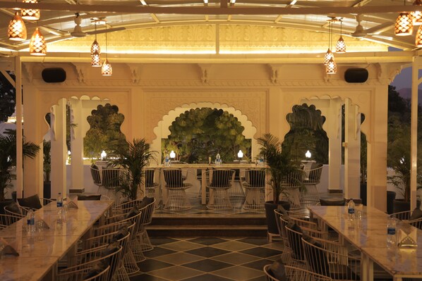 An indoor dining area with a long table, chairs, and decorative arches.