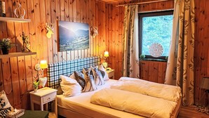 Um quarto acolhedor de madeira com uma cama, um quadro e uma janela com cortinas.