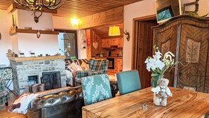 Uma sala de estar acolhedora com lareira, sofá de couro e uma mesa de jantar de madeira.