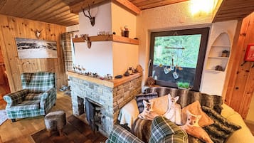 Un salon chaleureux avec une cheminée en pierre, des meubles à motifs écossais et une tête de cerf accrochée au mur.