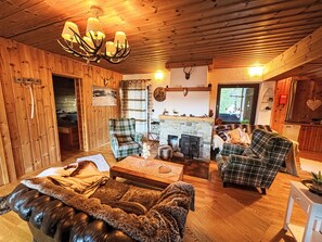 A cozy cabin interior with a fireplace, plaid furniture, and a wooden ceiling. - Apartment Silvia by Interhome (Sankt Margarethen im Lungau)