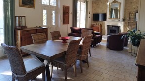 Un salon spacieux avec une table à manger en bois, des chaises en osier, un canapé et une cheminée.