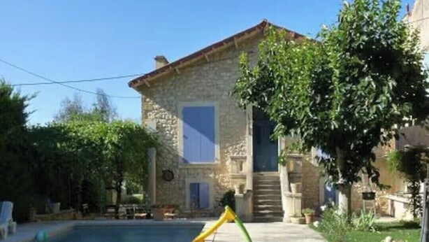 Une maison en pierre avec une piscine, un toboggan et des bouées gonflables.