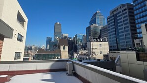 Una terraza con vistas al horizonte de una ciudad, con edificios modernos y un cielo azul despejado.
