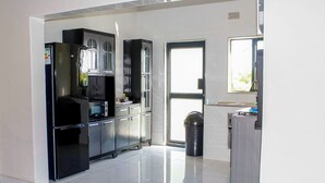 A modern kitchen with stainless steel appliances, a trash bin, and a window providing natural light. - Tou Safari Lodge (Livingstone)
