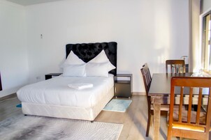 Een keurig opgemaakt slaapkamer met een bed, nachtkastjes, een bureau en een stoel.