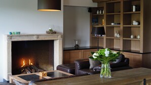 Una sala de estar con chimenea, un sofá, una mesa de centro y una estantería.