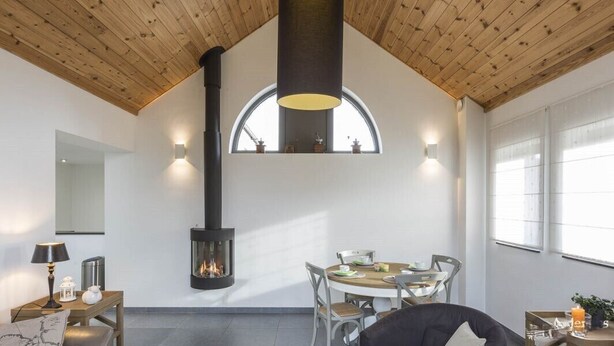 Una habitación acogedora con chimenea, techo de madera y una mesa de comedor con sillas.