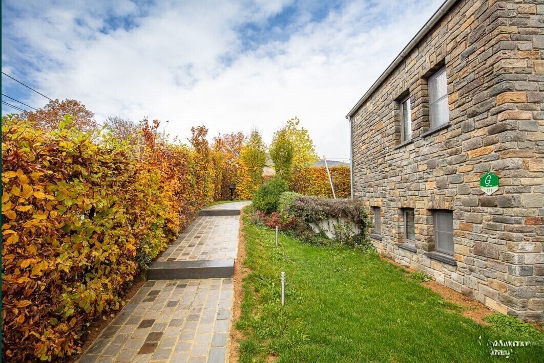 Un bâtiment en pierre avec un chemin pavé menant à une zone herbeuse.