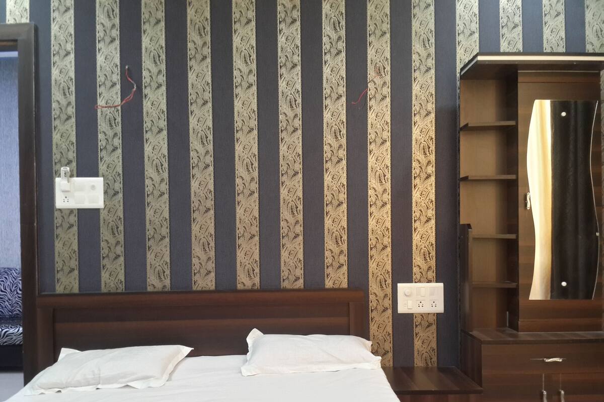 A hotel room with a bed, a wooden headboard, a wardrobe, and a mirror.