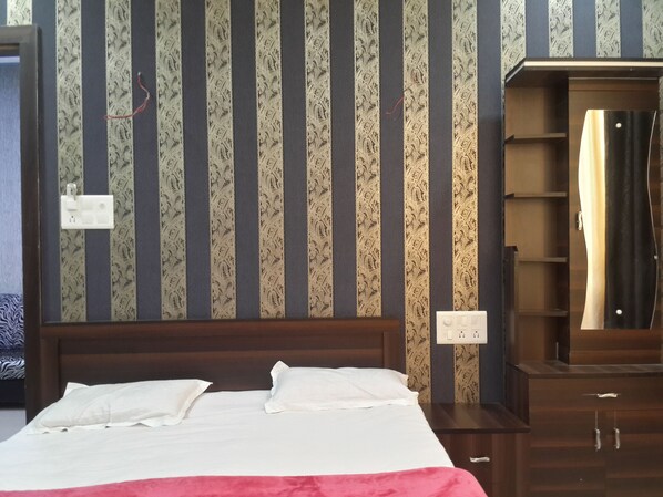 Una habitación de hotel con cama, cabecero de madera, armario y espejo.