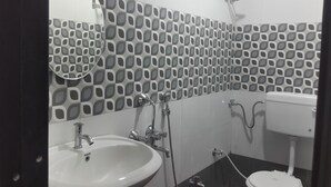 Een badkamer met een betegelde spatwand, een wit wastafel en een toilet.