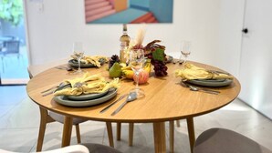 Une table ronde dressée pour un repas, avec de l’assiette, des couverts et un centre de table composé de fruits et de fleurs.