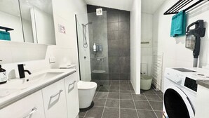 Une salle de bain moderne équipée d’une douche, de toilettes et d’un lave-linge.