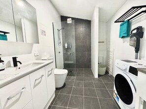 Un bagno moderno con doccia, WC e lavatrice.