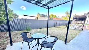 Une terrasse extérieure dotée d’un espace salon abrité, d’une table ronde et de chaises.