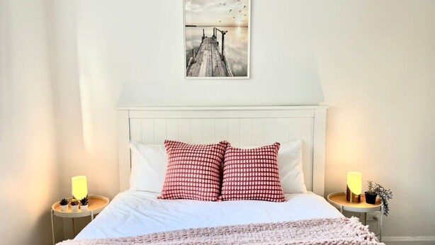 Une chambre à coucher avec un lit, des oreillers, des tables de chevet, une lampe, un tableau décoratif et une couverture.