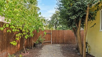 A backyard with a gravel path, a wooden fence, and a tree.