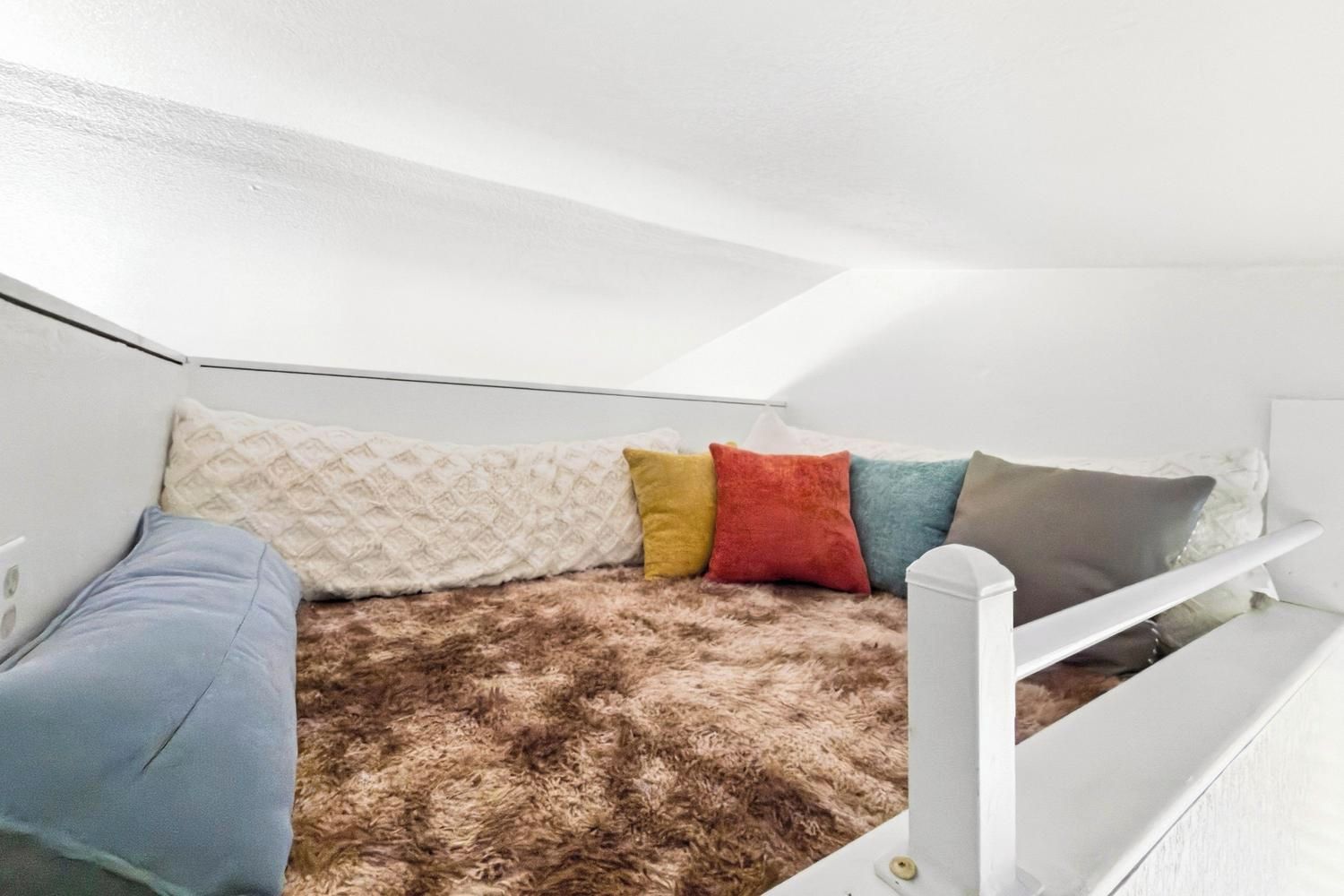 A small, cozy room with a bunk bed, a fluffy brown rug, and a white headboard.