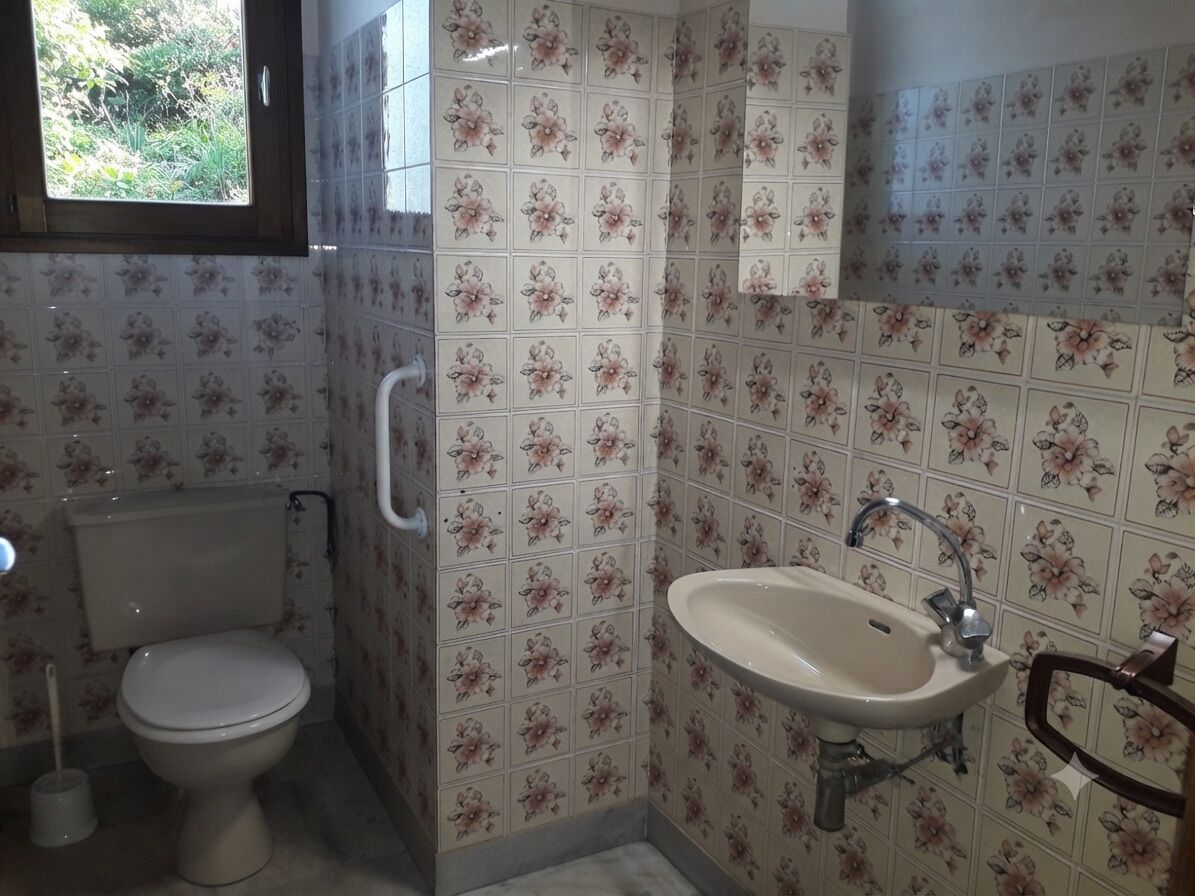 A bathroom with a toilet, a sink, and a window.