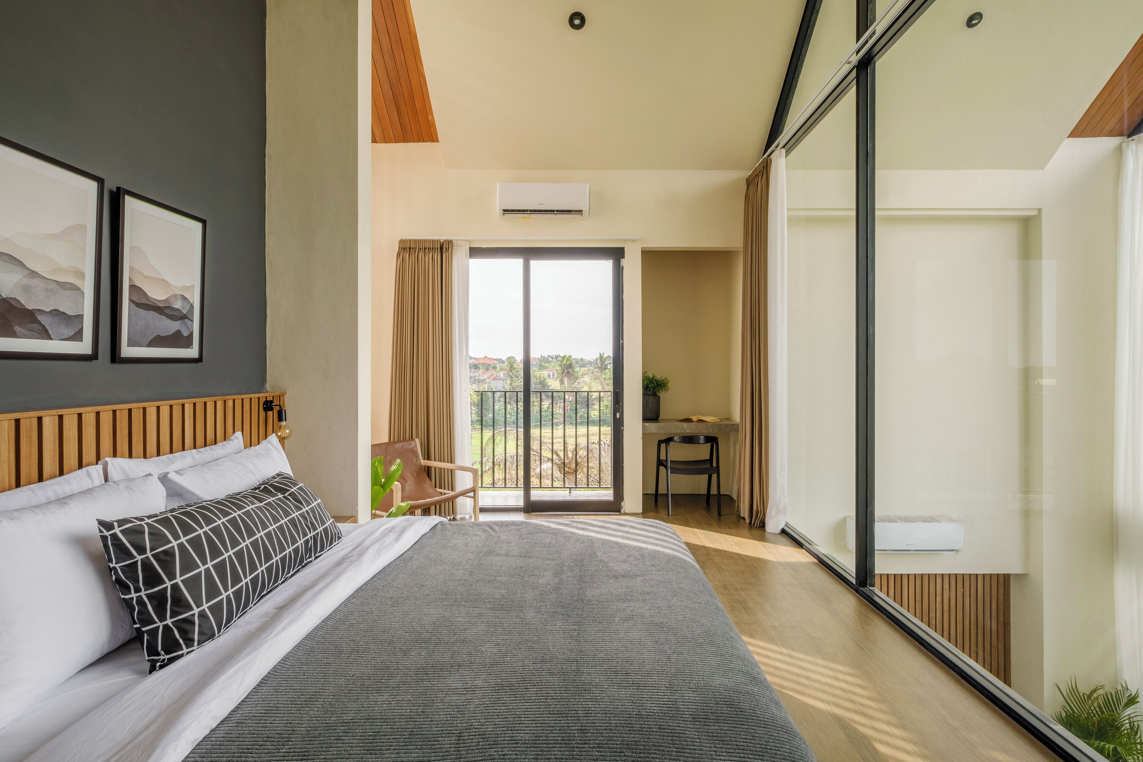 A modern hotel room with a large bed, a desk, and a balcony with a view.