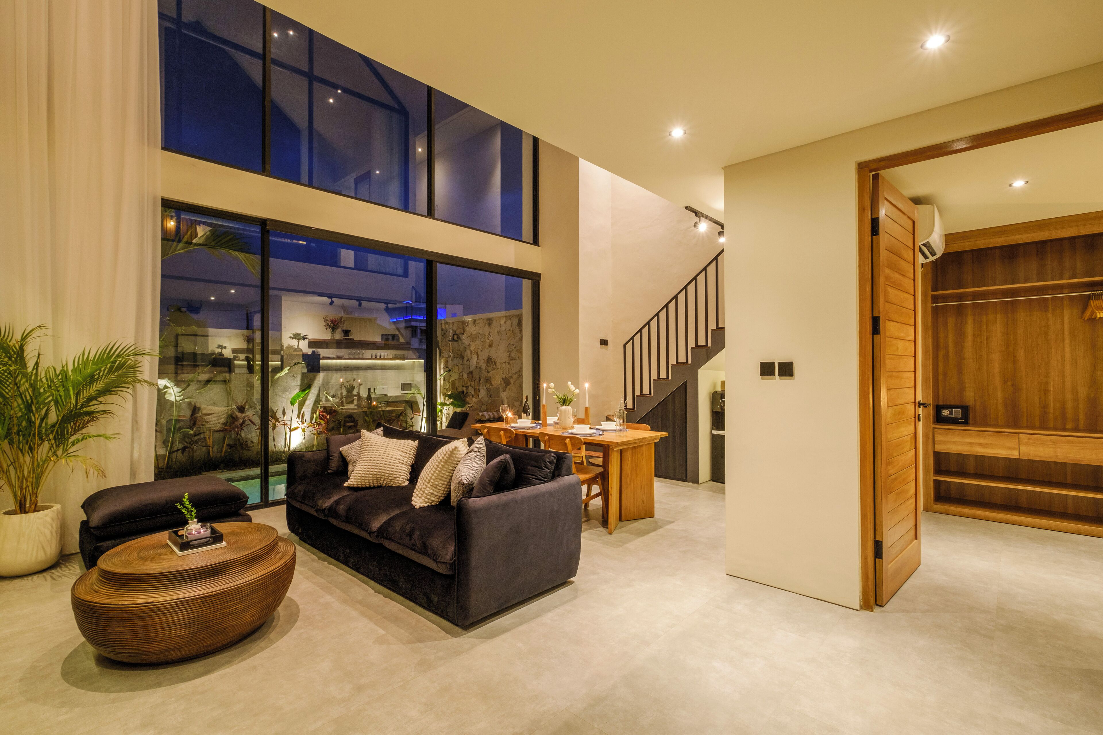 A modern living room with a dark sofa, a round coffee table, and a dining area with a wooden table and chairs.
