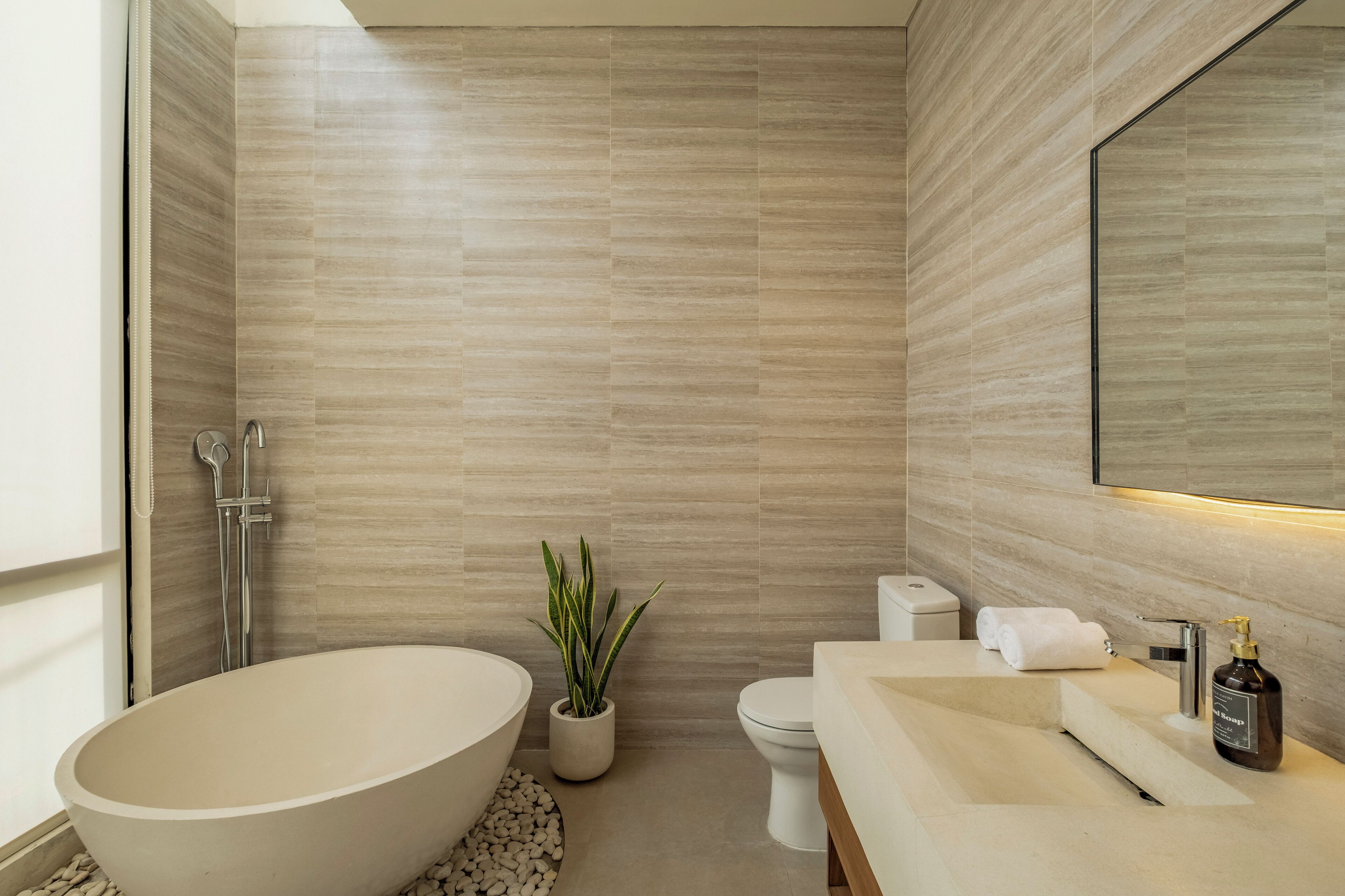 A modern bathroom with a freestanding bathtub, a toilet, and a sink with a mirror above.