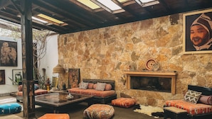 A cozy lounge area with a stone wall, a fireplace, and comfortable seating. - Surfiscamp (Dakhla)