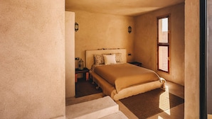 A bedroom with a large bed, a nightstand, a window, and a door. - Surfiscamp (Dakhla)