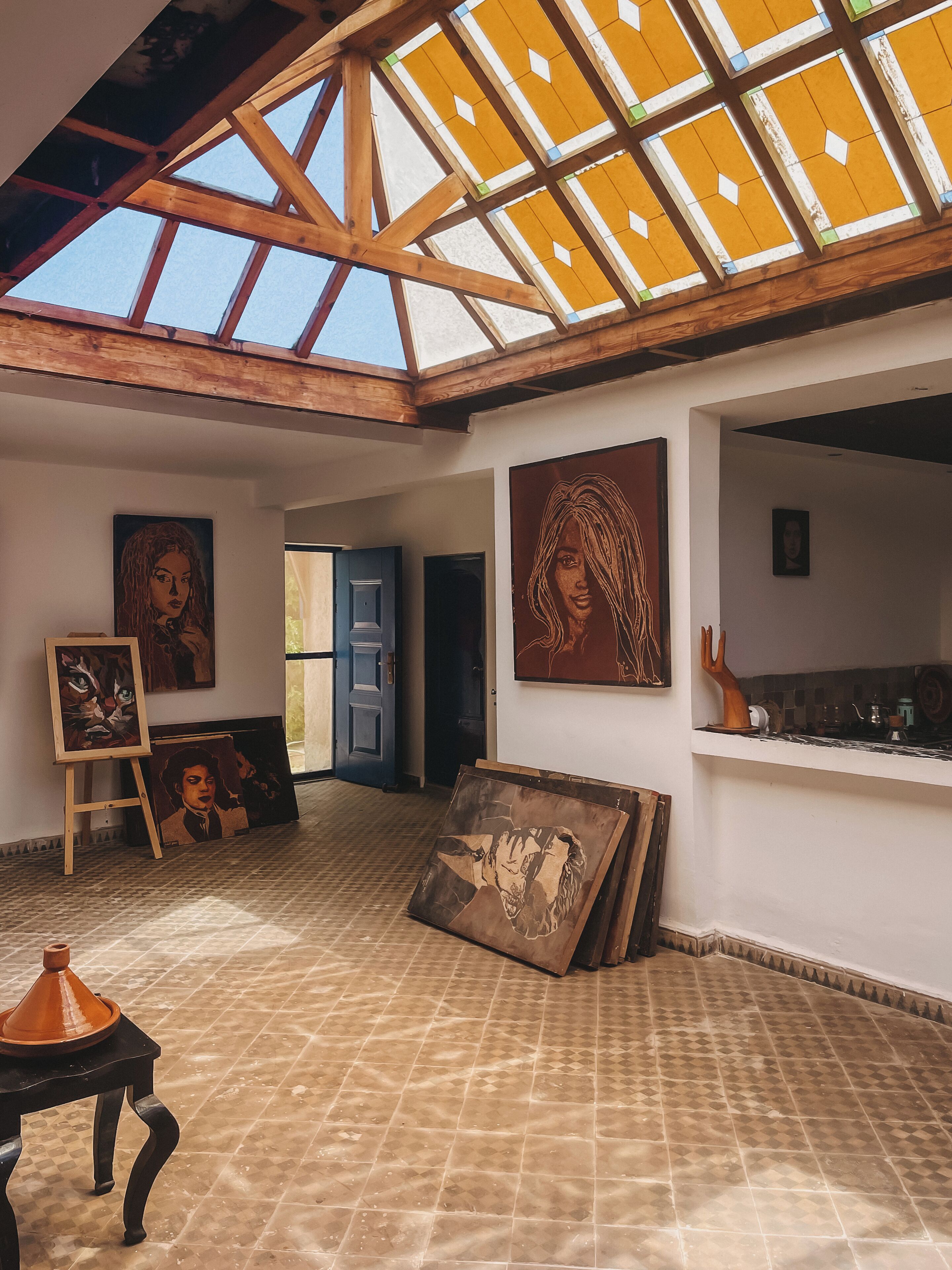 A spacious room with a high ceiling, skylight, and artwork on the walls.