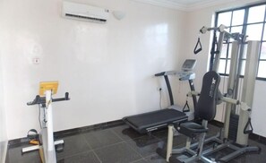 Ein Fitnessraum mit Laufband, Gewichte-Trainingsgerät und einer Bank.