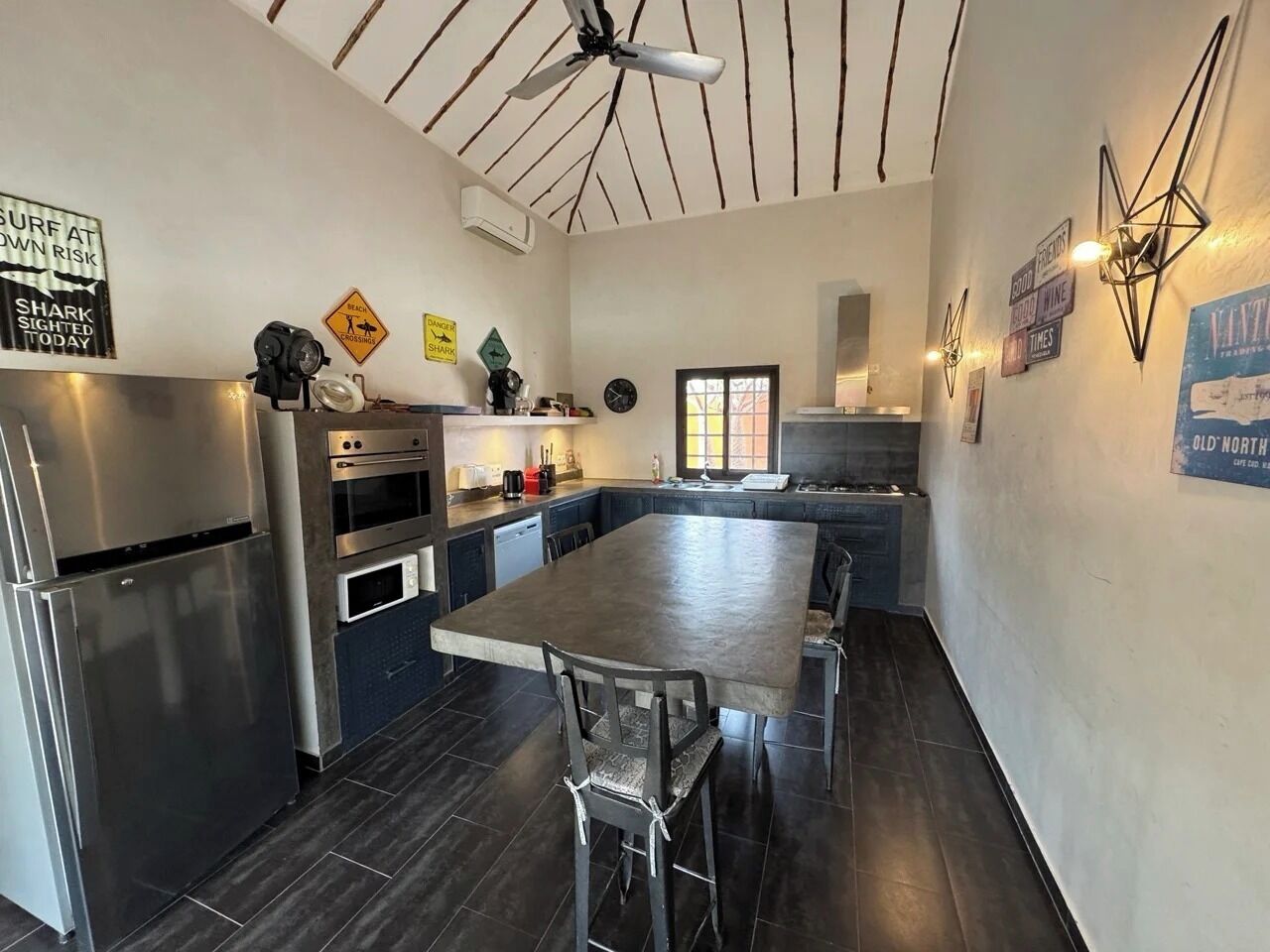 A modern kitchen with a central island, stainless steel appliances, and a ceiling fan.