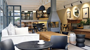 An indoor seating area with tables and chairs, a fireplace, and a bar area with shelves of bottles.