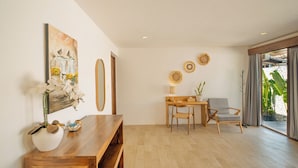 Un soggiorno moderno con una panca in legno, una scrivania e una sedia. Al muro, un quadro e sulla scrivania, una pianta in vaso.