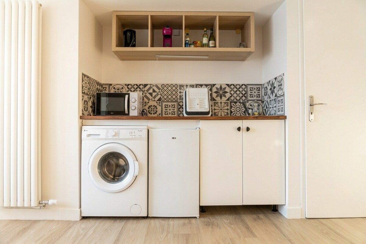 A laundry area with a washing machine and dryer, a microwave, and a shelf with bottles.