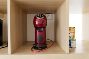 A red electric kettle on a wooden shelf with a power outlet in the background. - L’Épure - Terrasse & Parking Free (Tassin-la-Demi-Lune)