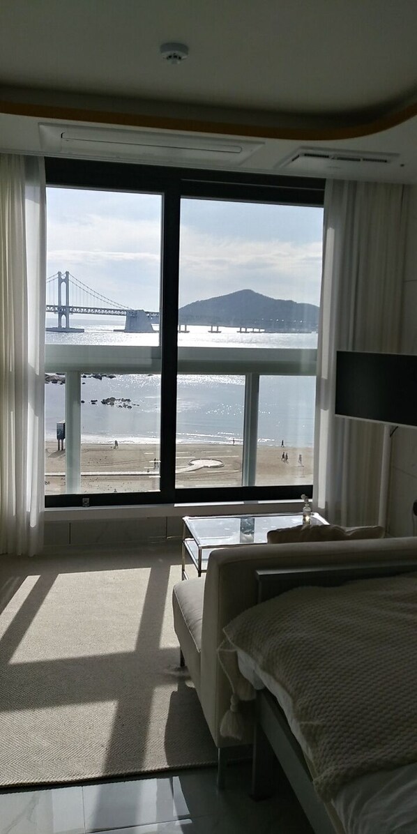 A hotel room with a large window offering a view of a bridge and beach. - 3seconds on the beach.Cozy 1-bedroom building in soothing Busan with A/C comfort (Busan)