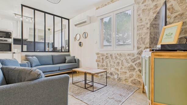 Un salon moderne avec un canapé gris, une table basse et un mur en pierre.