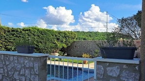 Une piscine en pierre, entourée d’une clôture métallique, de verdure et sous un ciel dégagé.