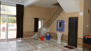 A spacious lobby with a marble floor, a staircase, and a large glass door leading outside. - Eagle Farm Stay Pushkar (Pushkar)