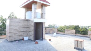 A rooftop terrace with a stone structure, a door, and a small table. - Eagle Farm Stay Pushkar (Pushkar)